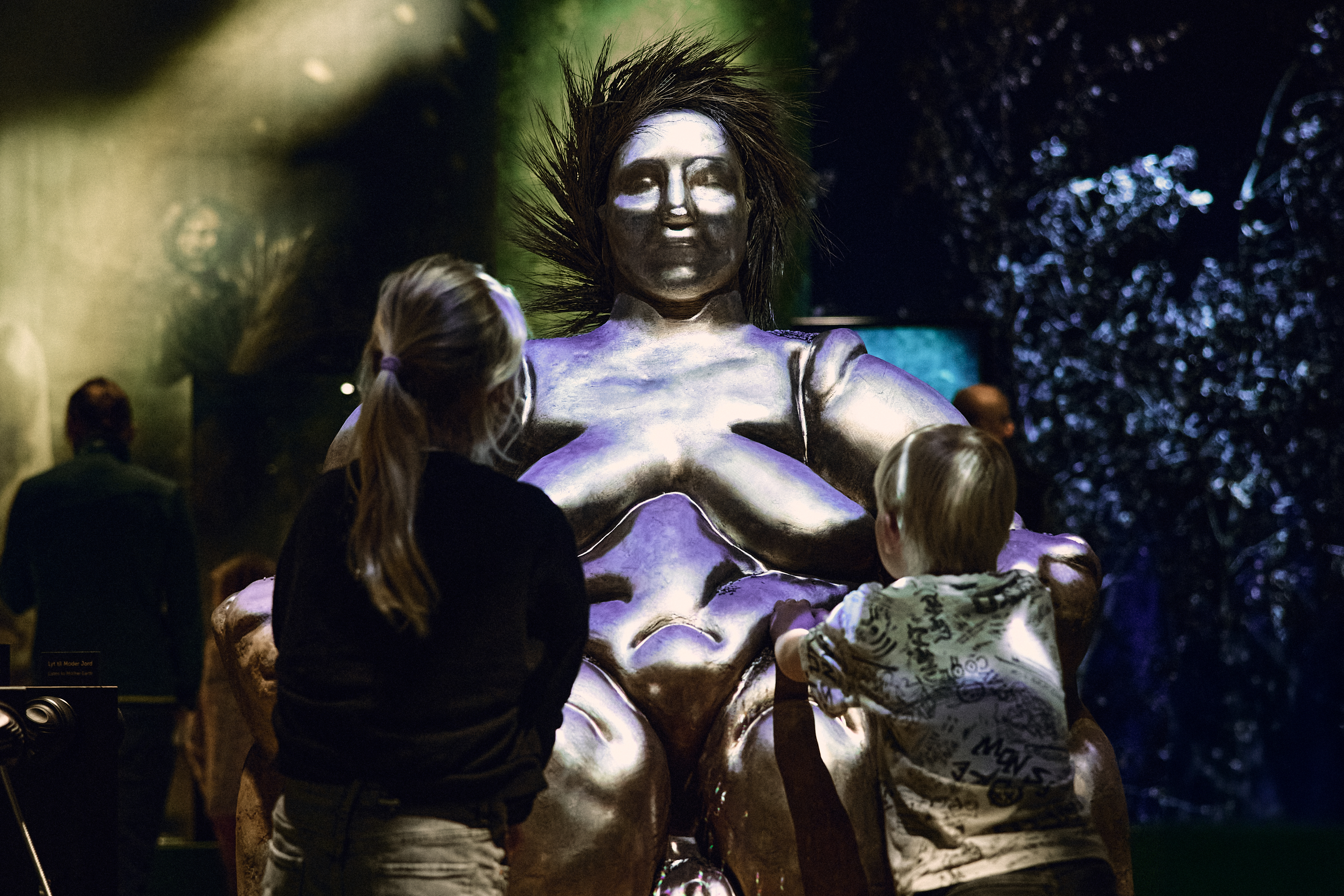 boern-kigger-paa-statue-af-tyk-kvinde